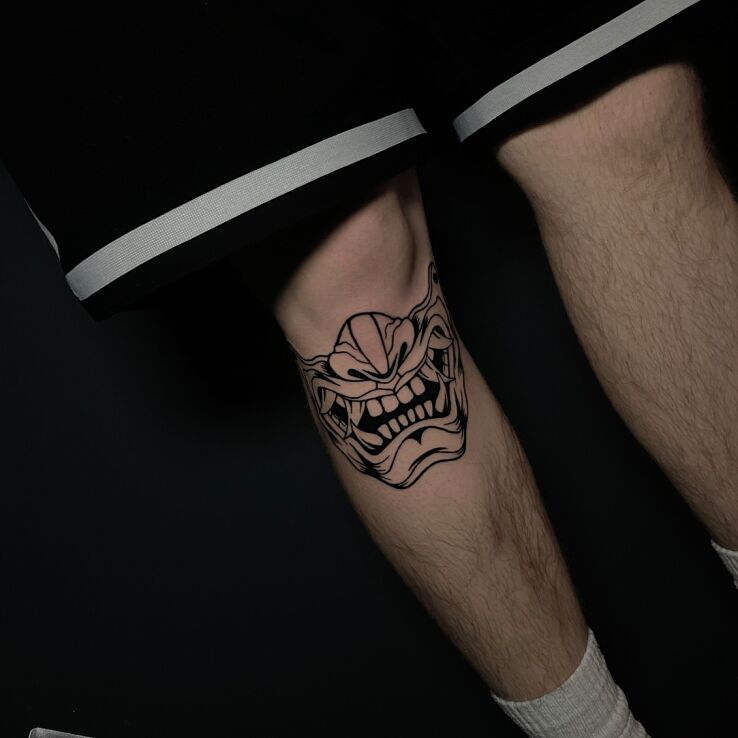 Tattoo Half Japanese Mask in black and gray motif and contour / linework style on the knee