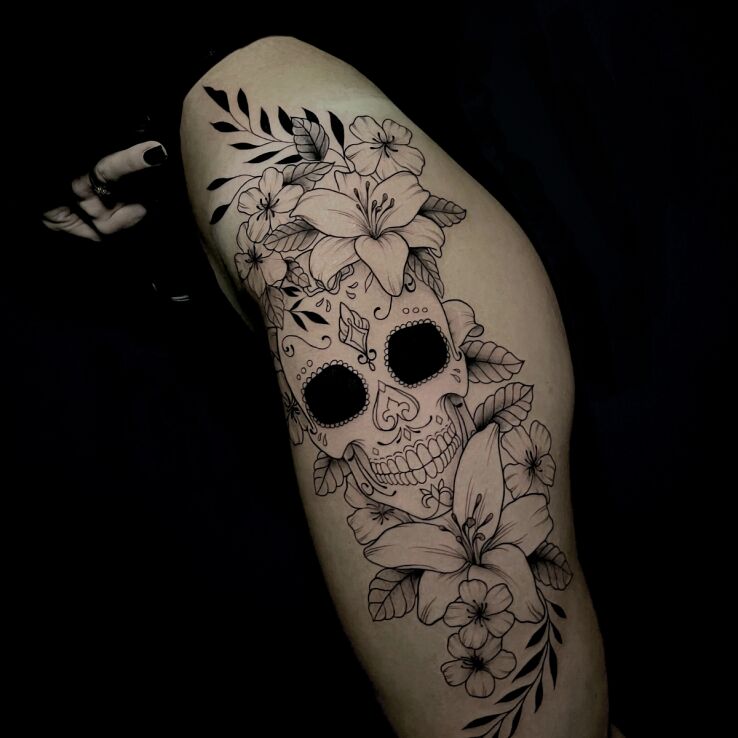 Tattoo Mexican skull with flowers in flowers motif and contour / linework style on the thigh
