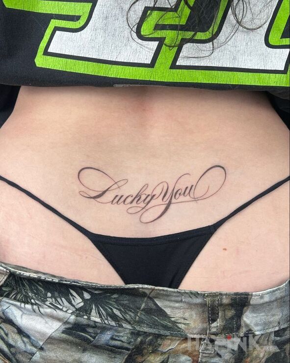 Tattoo Lucky you in black and gray motif and calligraphy style on the back
