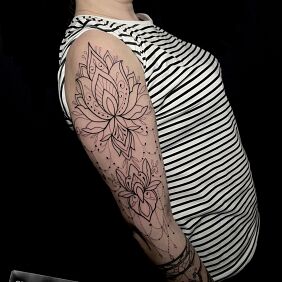 Tattoo Feminine tattoo with lotus flowers on the upper arm motif: ornaments style: contour / linework