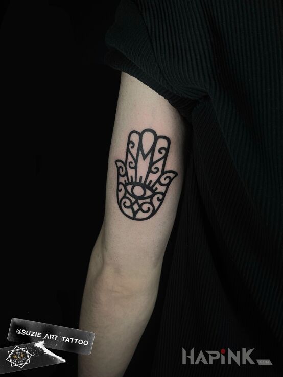 Tattoo Hamsa in religious motif and blackwork / blackout style On the arm