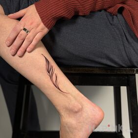 Tattoo Delicate Feather on the leg style: minimalistic