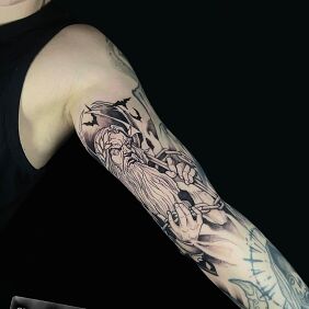 Tattoo Hades with chain against a background of bats On the arm motif: faces style: graphic / illustrative