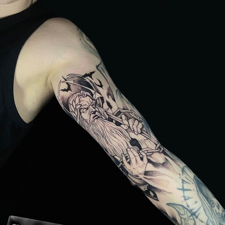 Tattoo Hades with chain against a background of bats in fantasy motif and graphic / illustrative style on the bicep