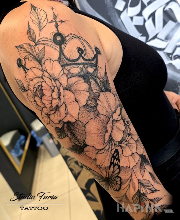 Tattoo Floral composition with crown and butterfly in black and gray motif and graphic / illustrative style on the upper arm