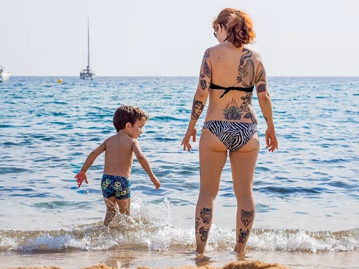 wytatuowana kobieta z dzieckiem na plaży