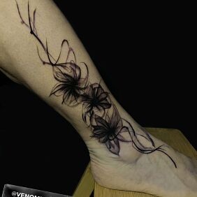 Tatuaż Czarne kwiaty z falowanymi wstawkami na nodze motyw: kwiaty styl: blackwork / blackout