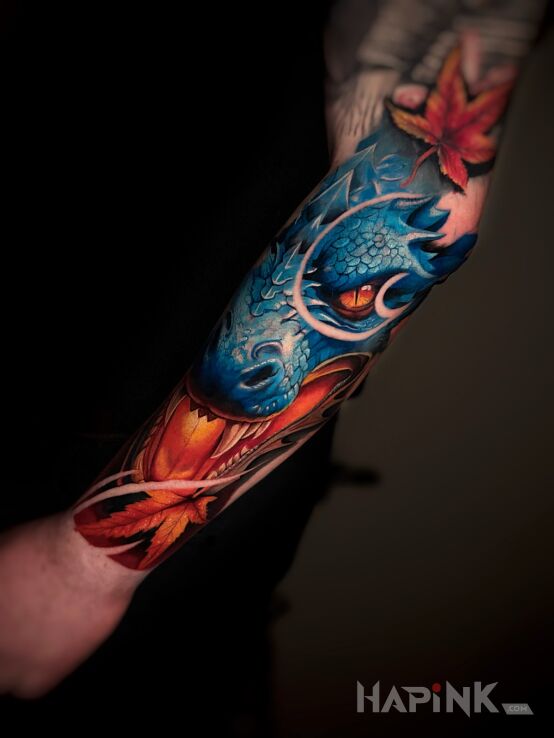 Tattoo Colorful dragon head with maple leaves in colorful motif and japanese / irezumi style on the forearm