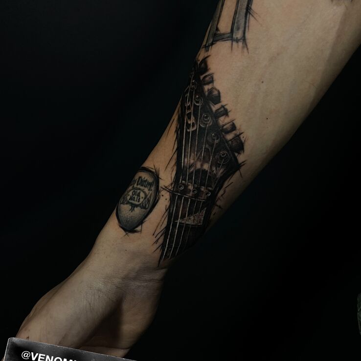Tattoo Guitar griffin in a dark style in objects motif and graphic / illustrative style on the forearm