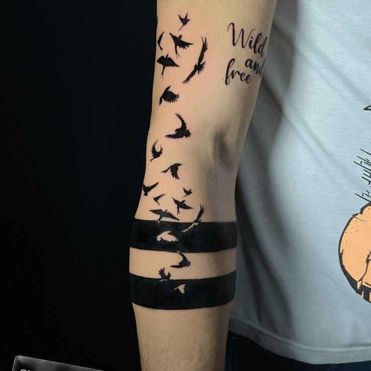 Tattoo Bracelet with flying birds in blackwork / blackout style On the arm
