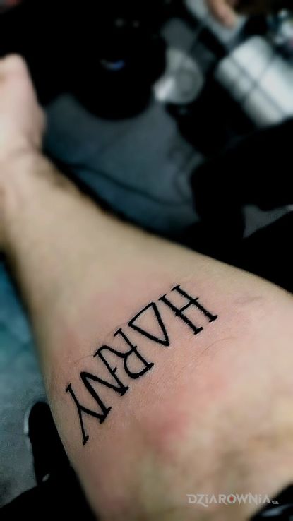 Tatuaż napis horny o zamienione na trójkąt w motywie napisy na przedramieniu