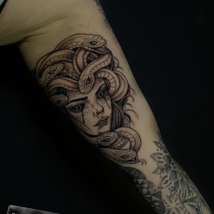 Tattoo Medusa in faces motif and graphic / illustrative style on the bicep