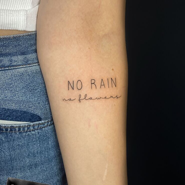 Tattoo No rain no flowers in lettering motif and minimalistic style On the arm