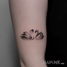 Tattoo Two swans forming a heart on the upper arm motif: animals style: minimalistic