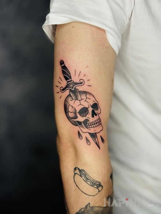Tattoo Dagger Piercing a Skull in skulls motif and oldschool style on the upper arm