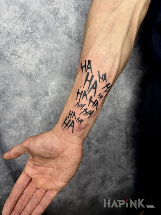Tattoo Ha ha ha in black and gray motif and blackwork / blackout style On the arm