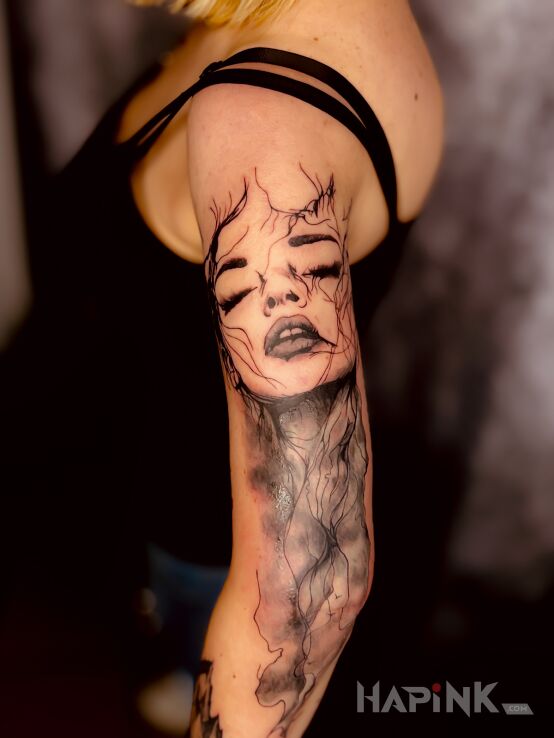 Tattoo Female face with closed eyes in black and gray motif and Watercolor style on the upper arm