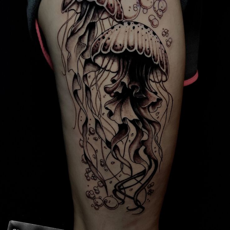 Tattoo Two jellyfish in black and gray motif and realistic style on the thigh
