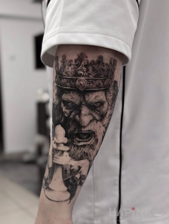 Tattoo King and chess piece in black and gray motif and realistic style on the forearm