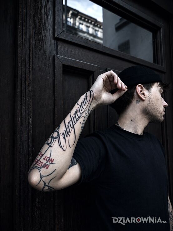 Tatuaż Lettering wykonany kursywą - entrepreneur w motywie napisy i stylu blackwork / blackout na ręce