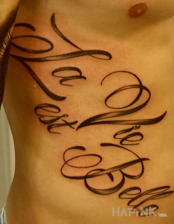Tattoo La Vie est Belle in lettering motif on the ribs