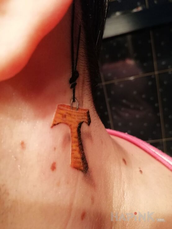 Tattoo Tauka in religious motif behind the ear