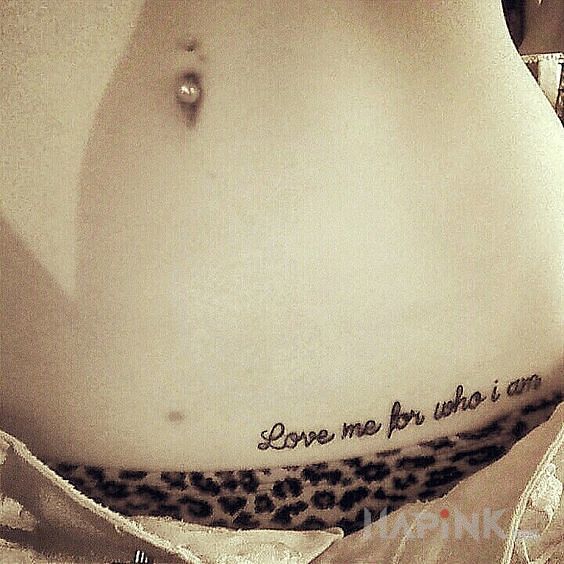 Tattoo Kochaj mnie in lettering motif and calligraphy style on the stomach