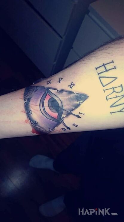Tattoo Oko opacznosci z zegarem in colorful motif on the forearm