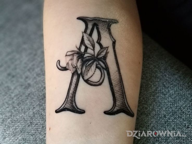 Tatuaż literka w motywie kwiaty na przedramieniu