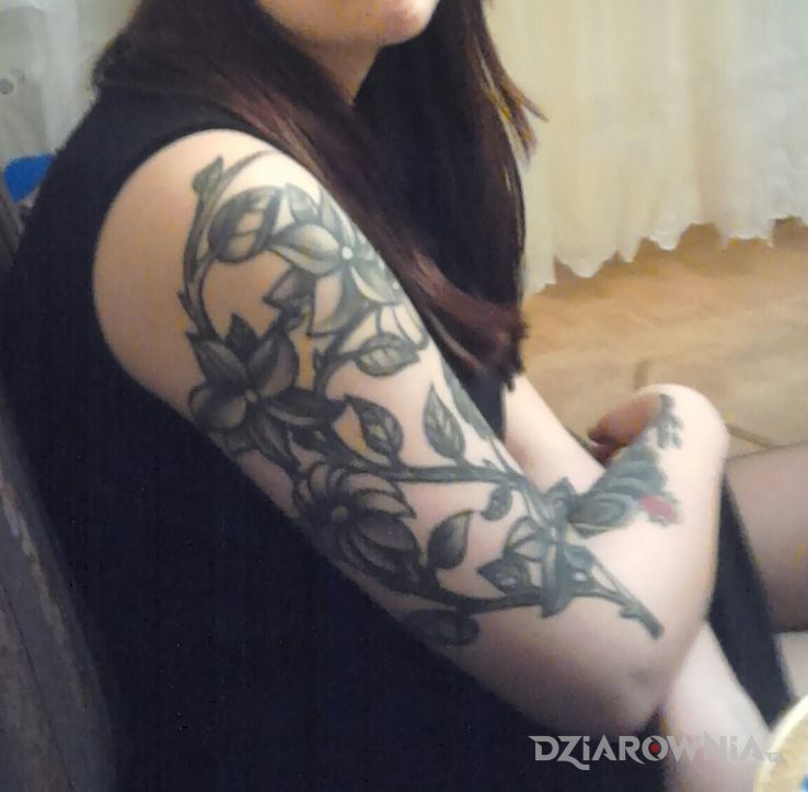 Tatuaż ķwiatowo w motywie kwiaty na ramieniu