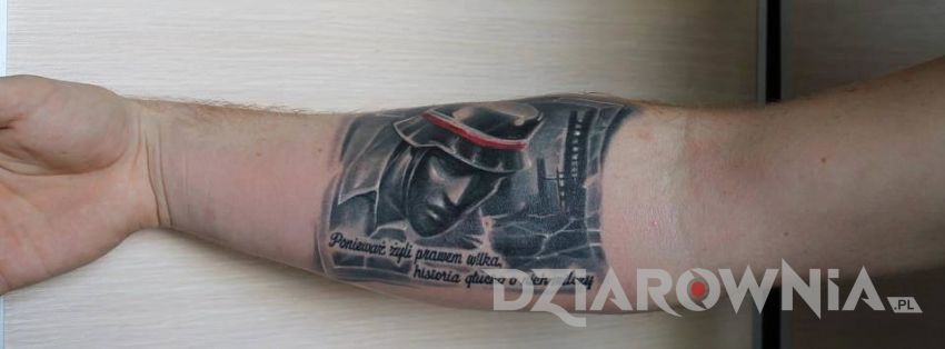 Tatuaż patriotyczny o żołnierzach wyklętych z cytatem na przedramieniu u meżczyzny