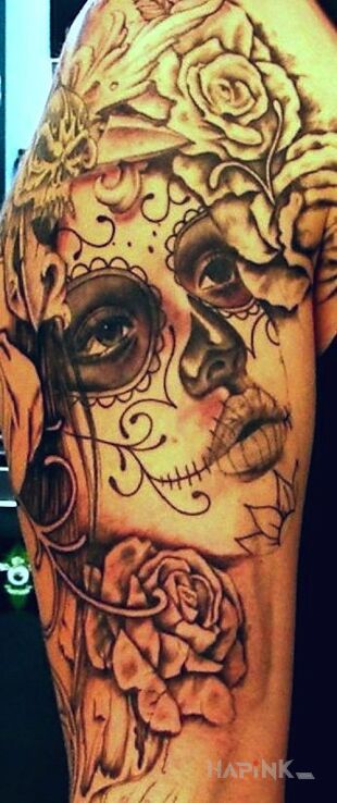 Tattoo Dia de los Muertos in faces motif on the upper arm