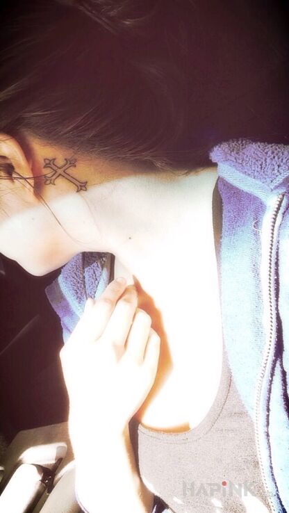 Tattoo Krzyżyk za uchem in religious motif and contour / linework style behind the ear