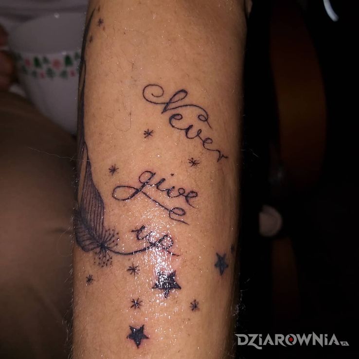 Tatuaż nigdy się nie poddawaj w motywie napisy i stylu kaligrafia na przedramieniu