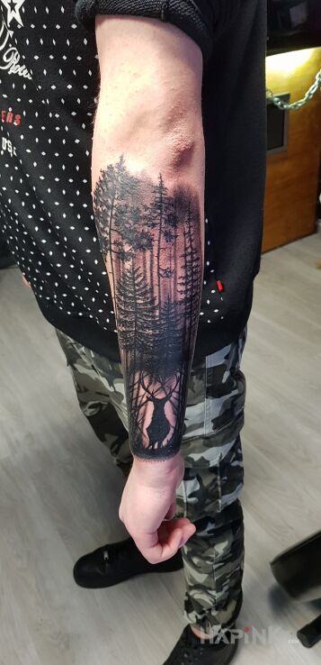 Tattoo Forest and Deer in black and gray motif and realistic style on the forearm