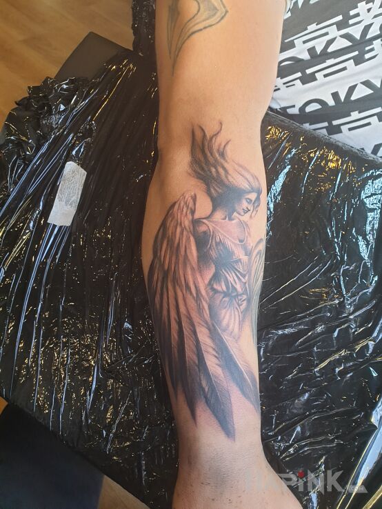 Tattoo Aniol in wings motif and realistic style on the forearm