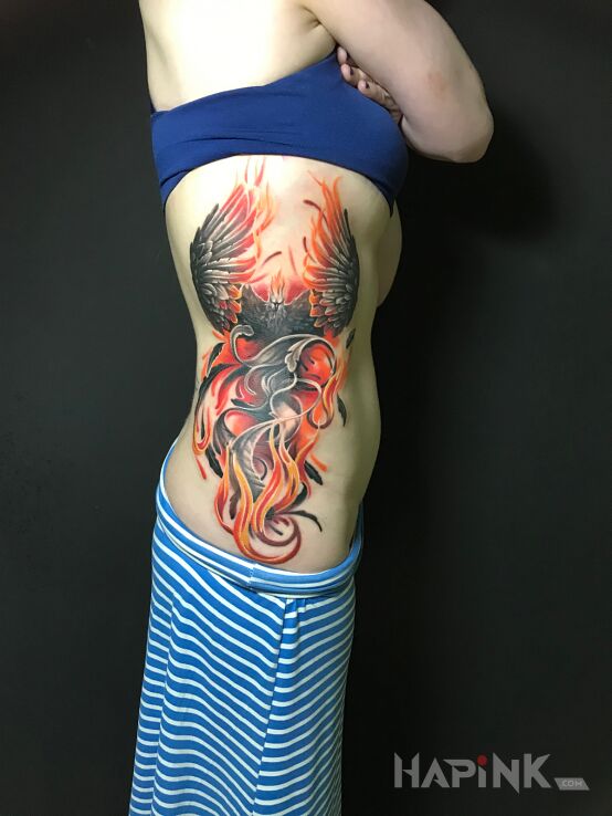 Tattoo FENIKS in fantasy motif and realistic style on the ribs