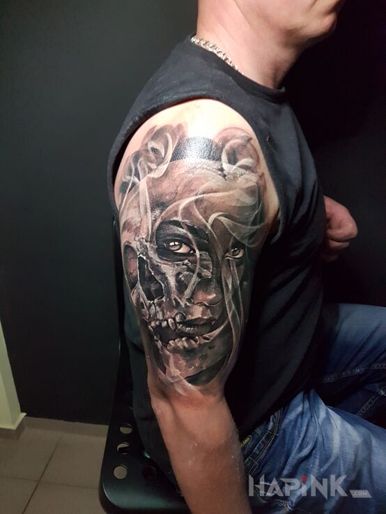 Tattoo 2Face in faces motif and realistic style on the upper arm