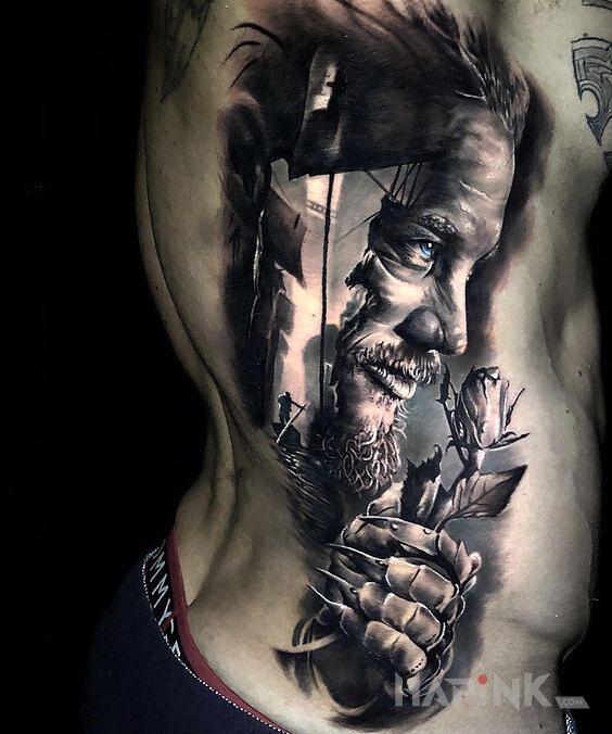 Tattoo Ragnar in black and gray motif and realistic style on the upper arm